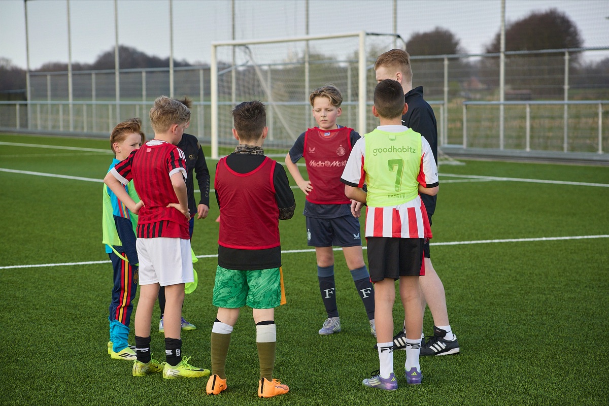 Trainer met jonge spelers tijdens een training van Janssen Voetbalschool